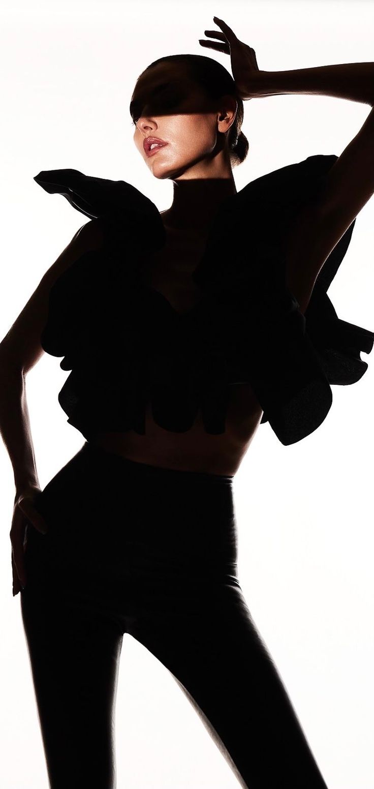 Woman in a ruffled top and high-waisted pants in a dramatic silhouette