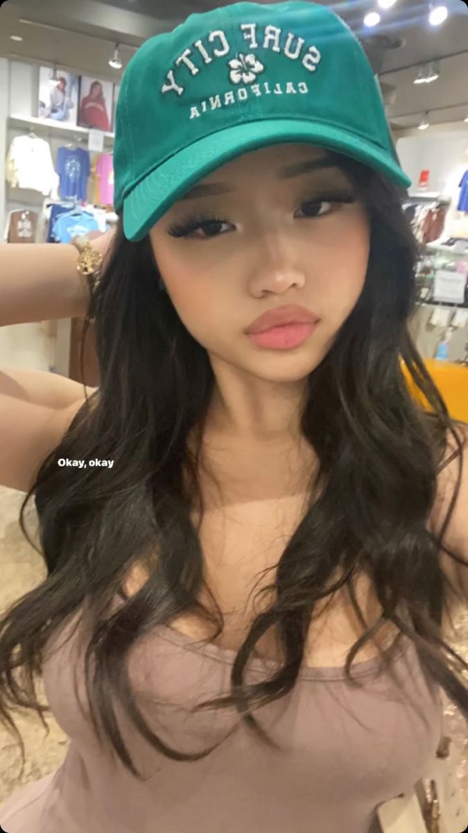Woman with long black hair and a green cap in a store