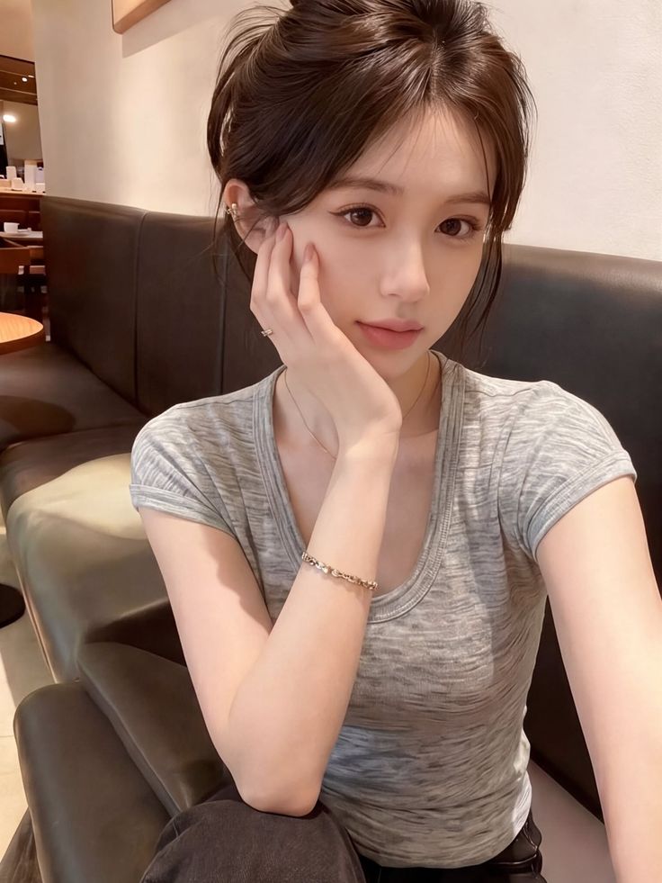 Woman with brown hair in a messy bun wearing a gray t-shirt indoors