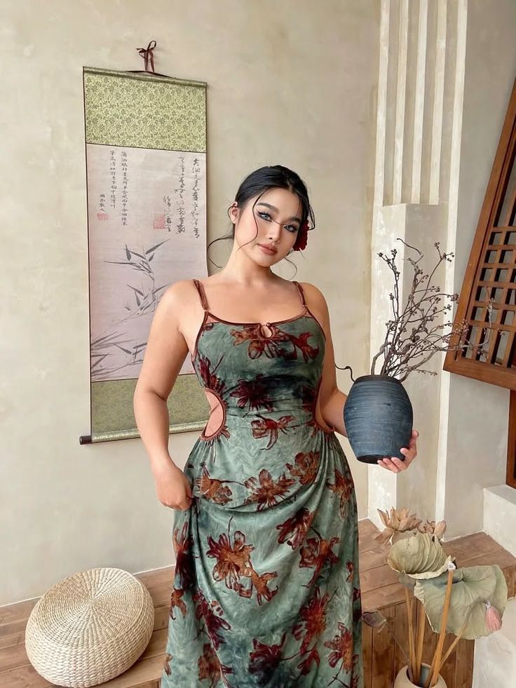 Woman in a floral dress with cutouts holding a vase indoors