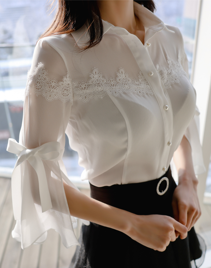 Woman in a white sheer blouse with lace details and a black skirt