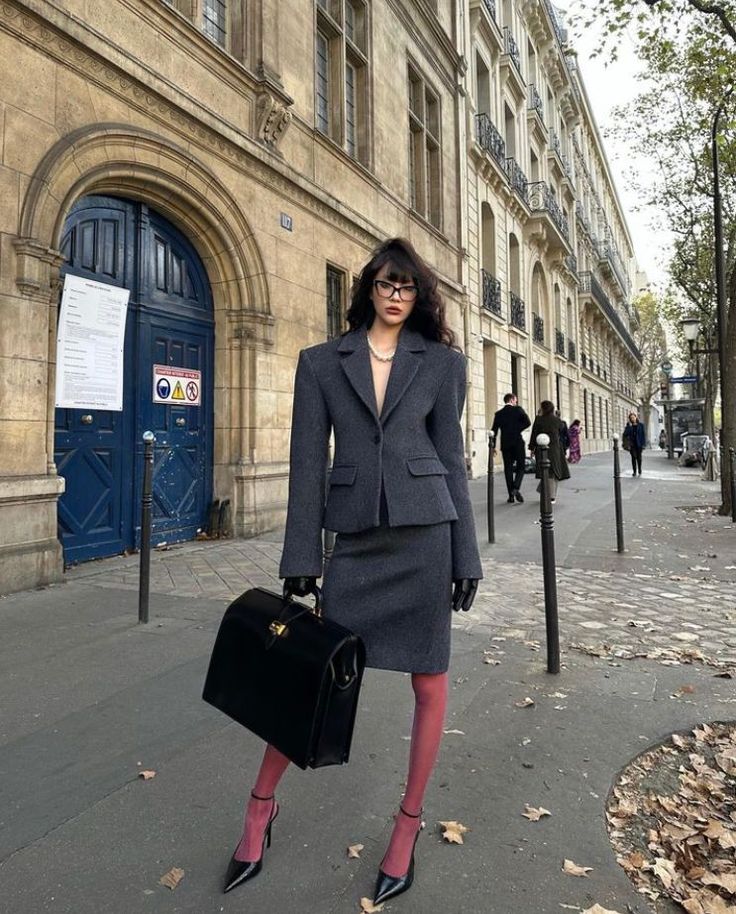 Woman in a grey skirt suit and pink tights on a city street