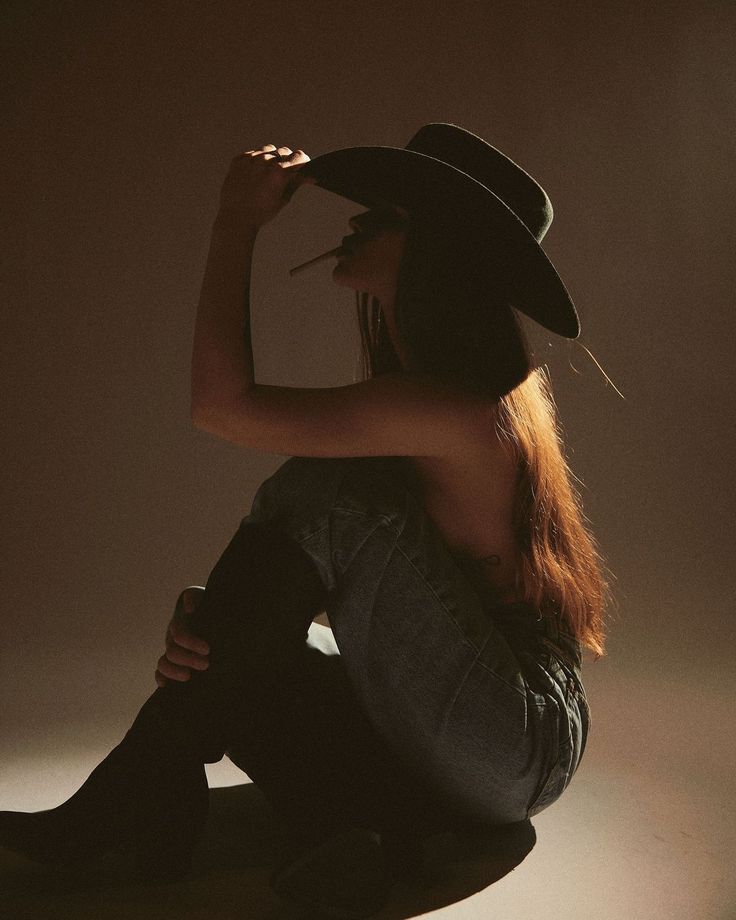 Woman in a cowboy hat and jeans, with long hair and backlight
