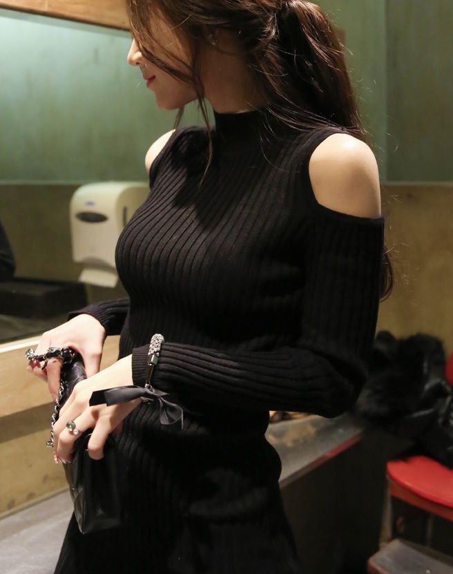 Woman in a black cold shoulder ribbed knit top indoors