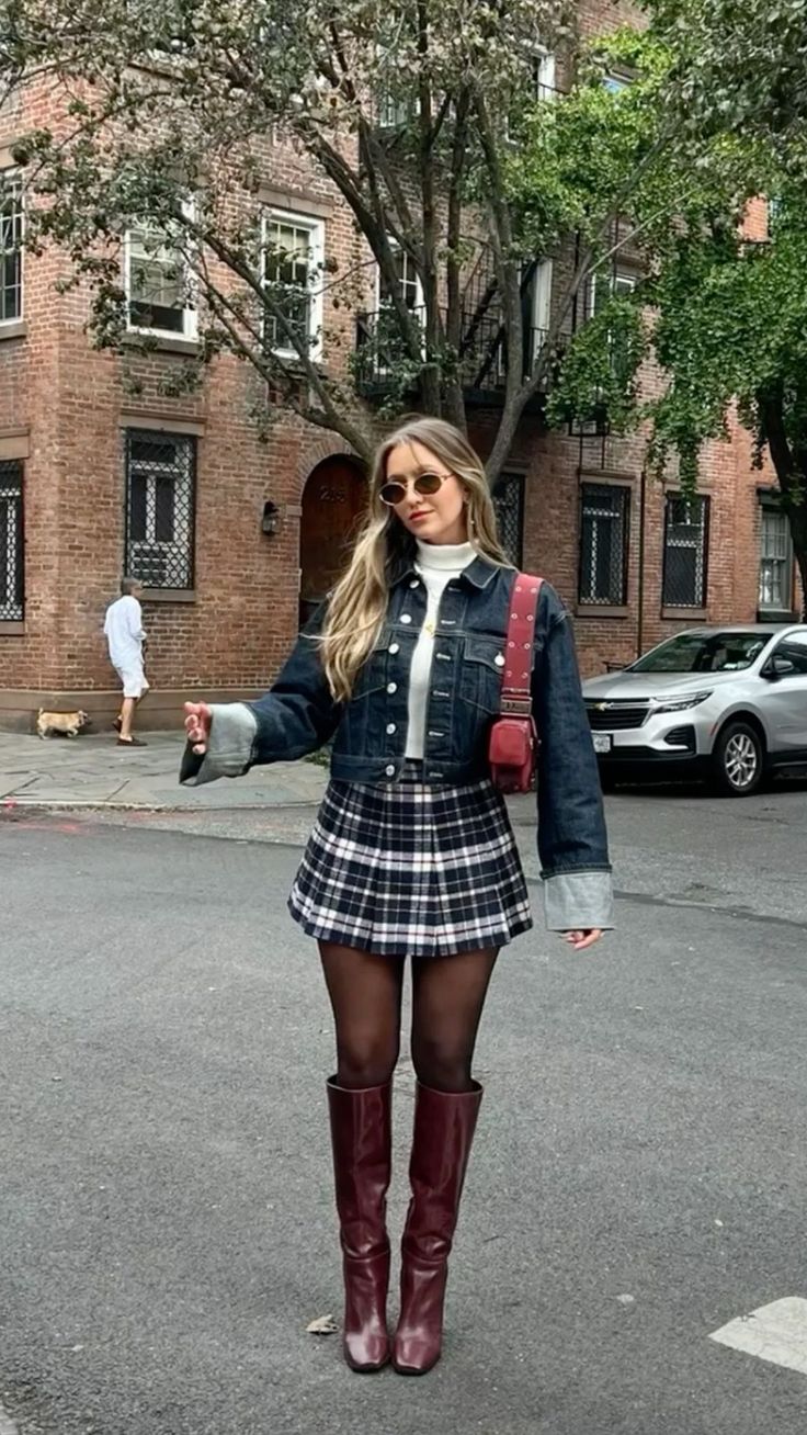 Woman in a denim jacket and plaid skirt on a city street