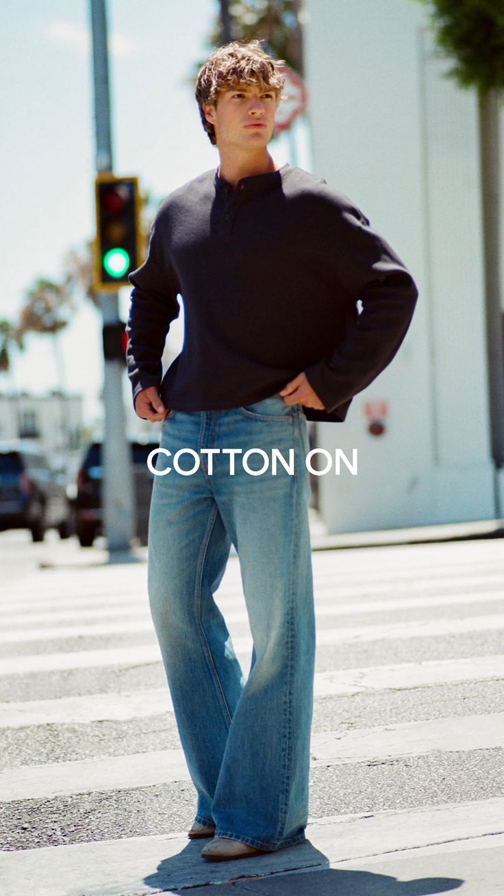 Man in a long sleeve shirt and wide leg jeans standing on a street