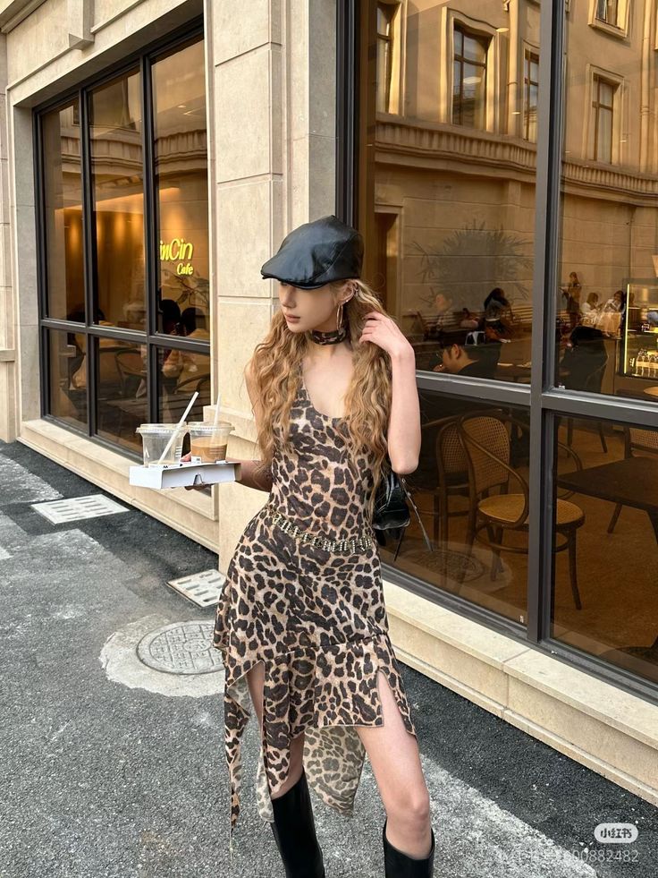 Woman in a leopard print dress and black hat holding drinks outside a cafe