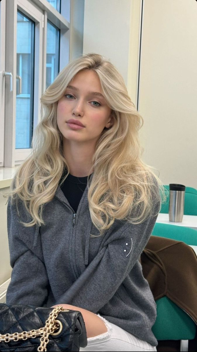 Woman with long blonde hair wearing a grey hoodie indoors