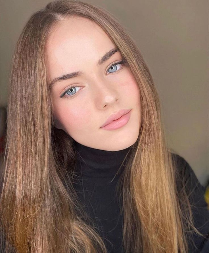 Woman with long hair and blue eyes wearing a black turtleneck