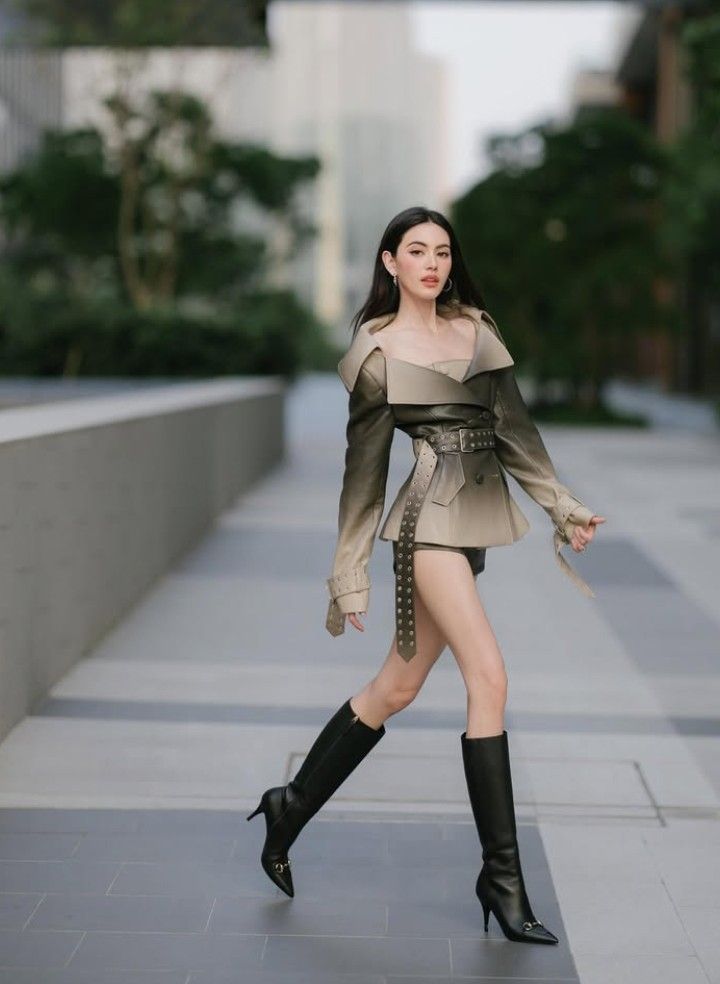 Woman in a stylish leather jacket and high boots walking outdoors