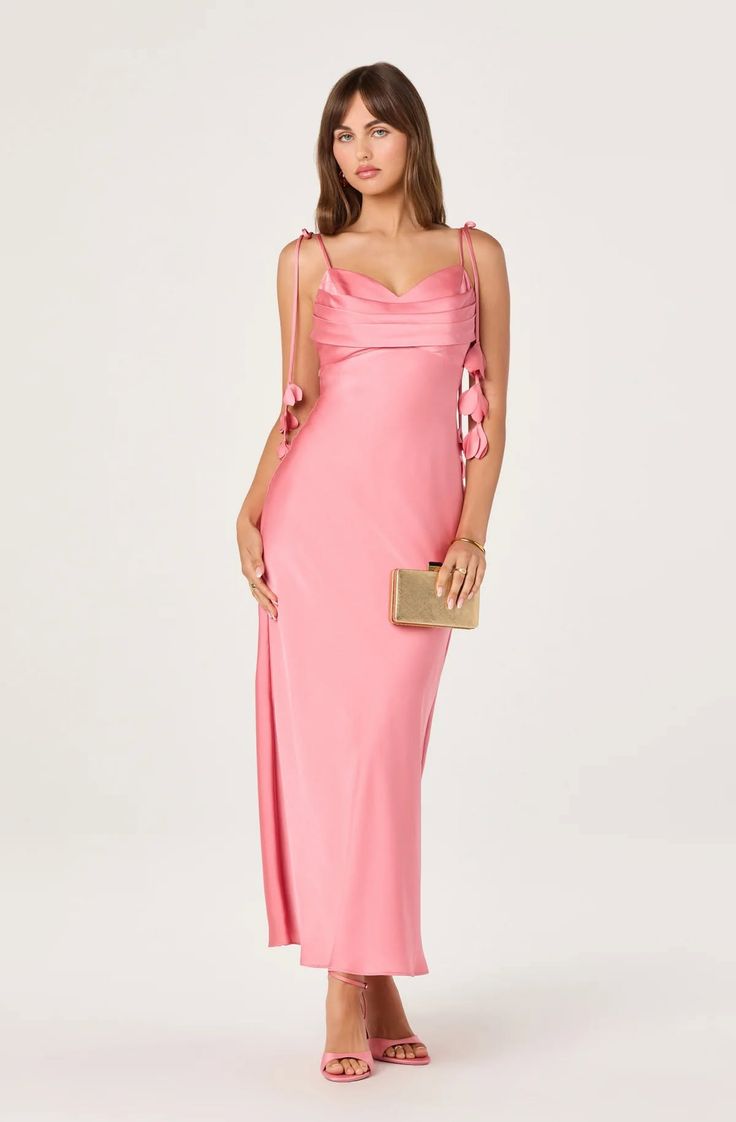 Woman in a pink dress holding a gold clutch in a studio setting