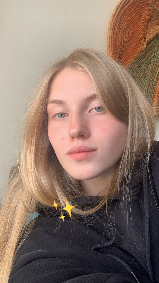 Young woman with blonde hair wearing a black hoodie indoors