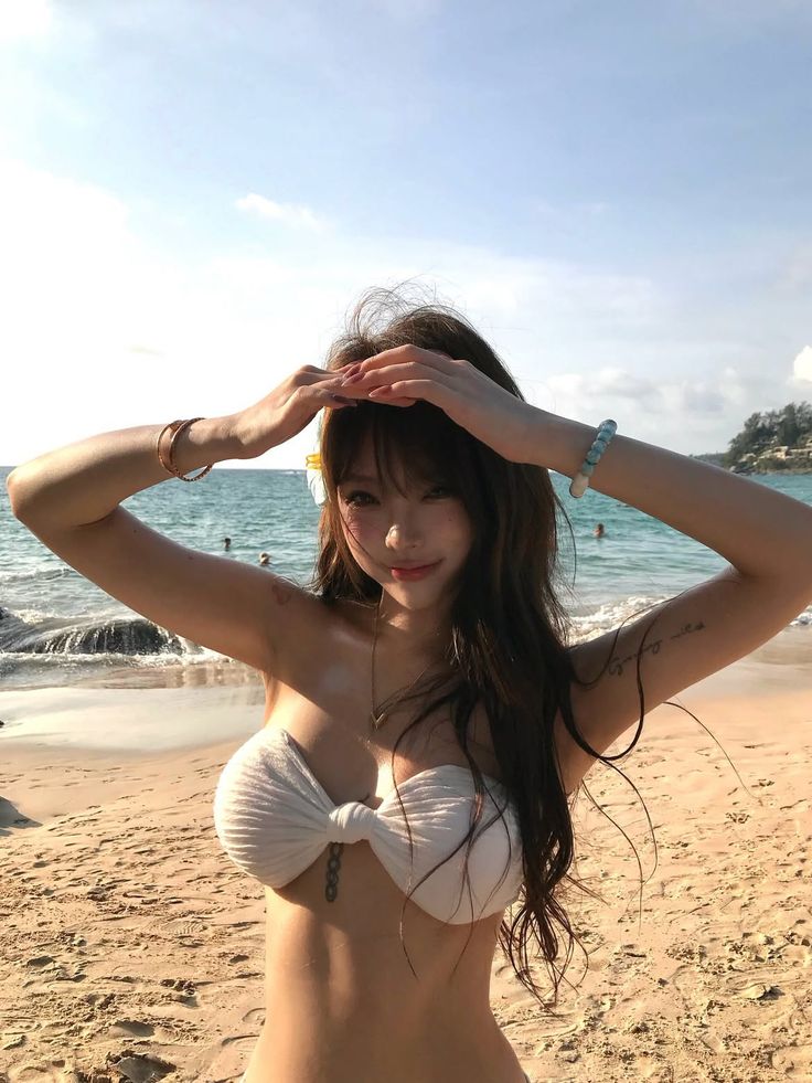 Woman in a white bikini top posing on a sunny beach