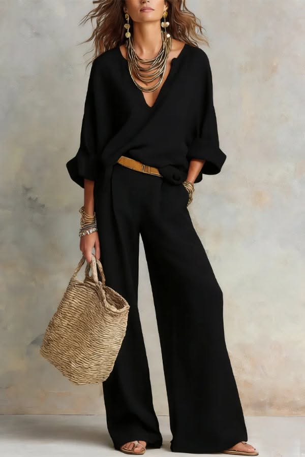 Woman in a black outfit with a straw bag and gold jewelry