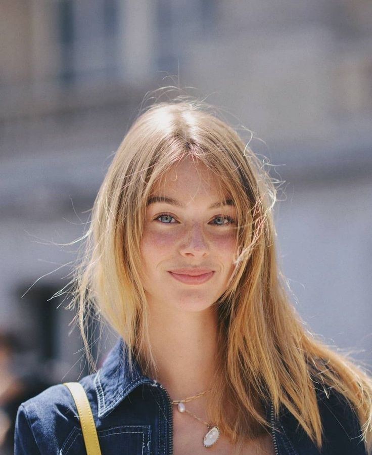 Young woman with blonde hair and freckles wearing a denim jacket and necklace