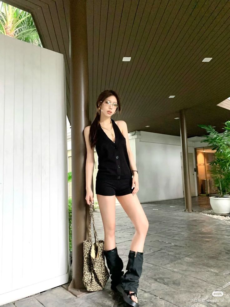 Woman in a black halter top and shorts with a leopard print bag outdoors