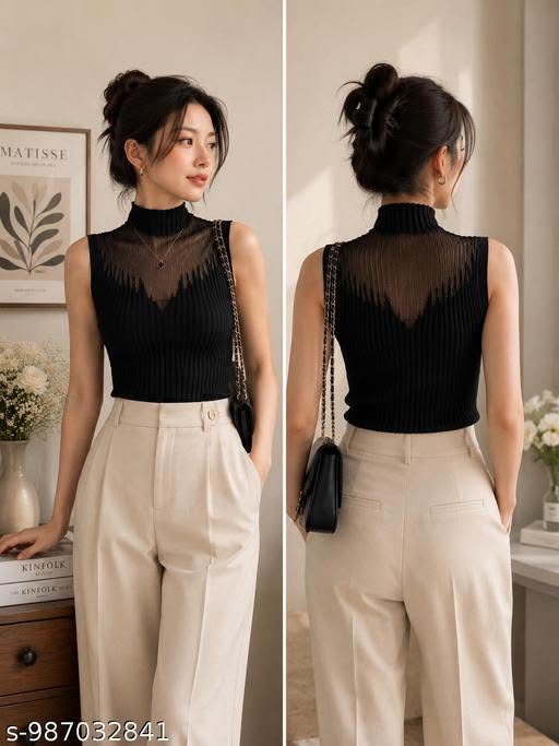 Woman in a black sheer top and beige pants posing indoors