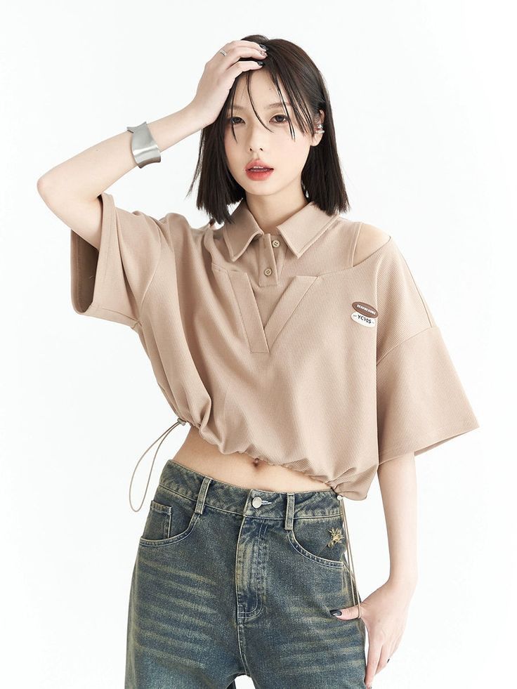 Woman with short hair wearing a cropped top and jeans, posing in a studio