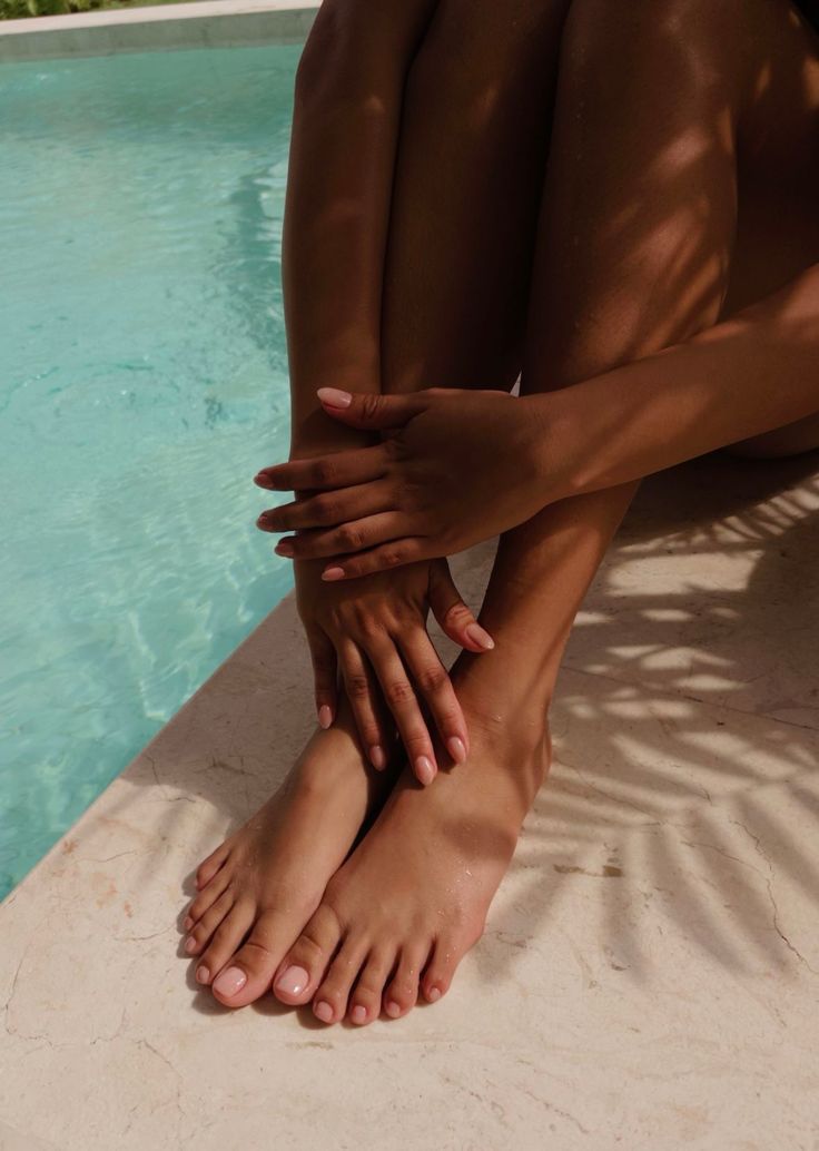 Bare feet and hands by a swimming pool with dappled sunlight
