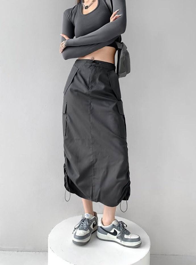 Person in a dark gray long sleeve crop top and cargo skirt with sneakers