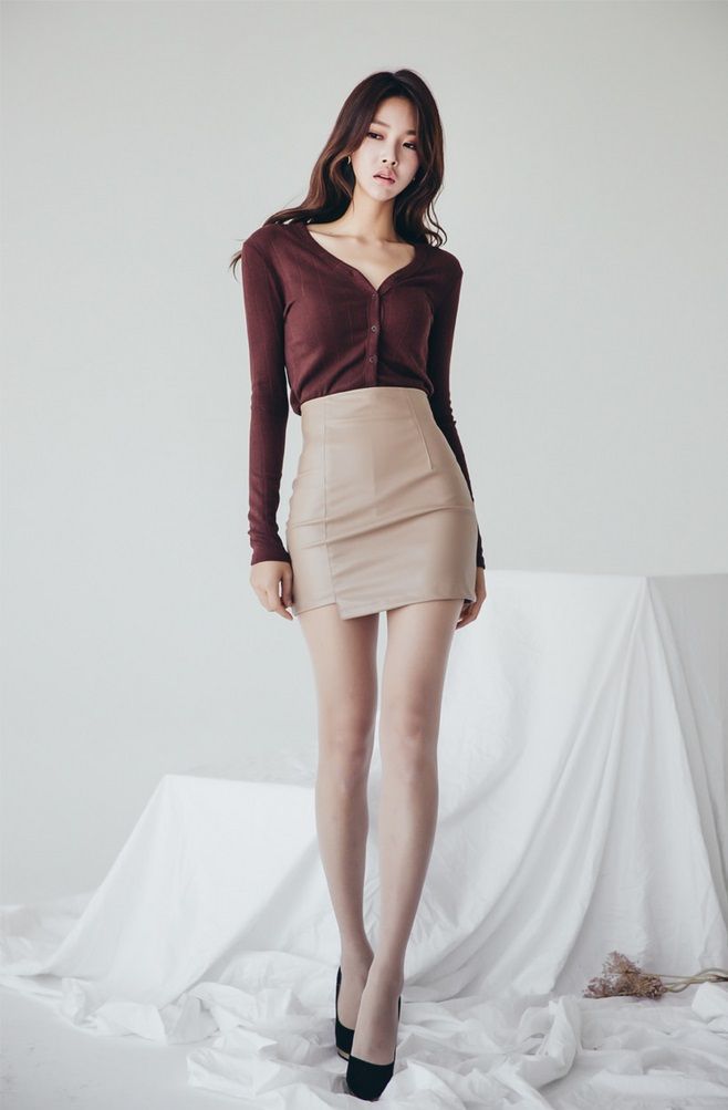 Woman with long hair wearing a cardigan and mini skirt in an indoor setting