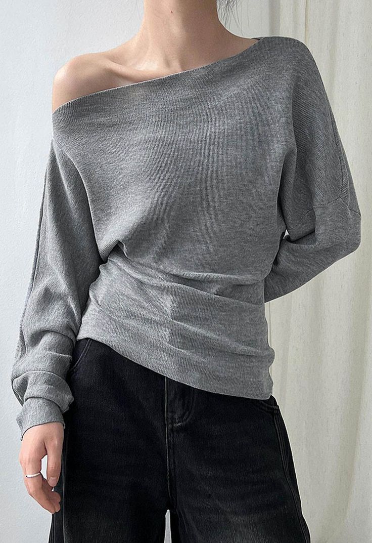 Person wearing a gray off-shoulder top and black jeans indoors