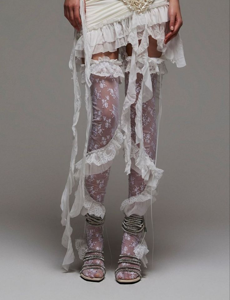 Person in a white ruffled dress with lace stockings and strappy sandals