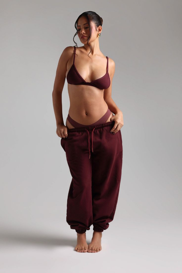 Woman in a maroon bra and sweatpants in a studio setting