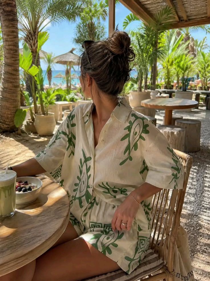 Woman in a patterned outfit at an outdoor cafe overlooking a beach