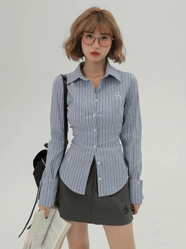 Woman with short hair and glasses wearing a striped shirt and mini skirt