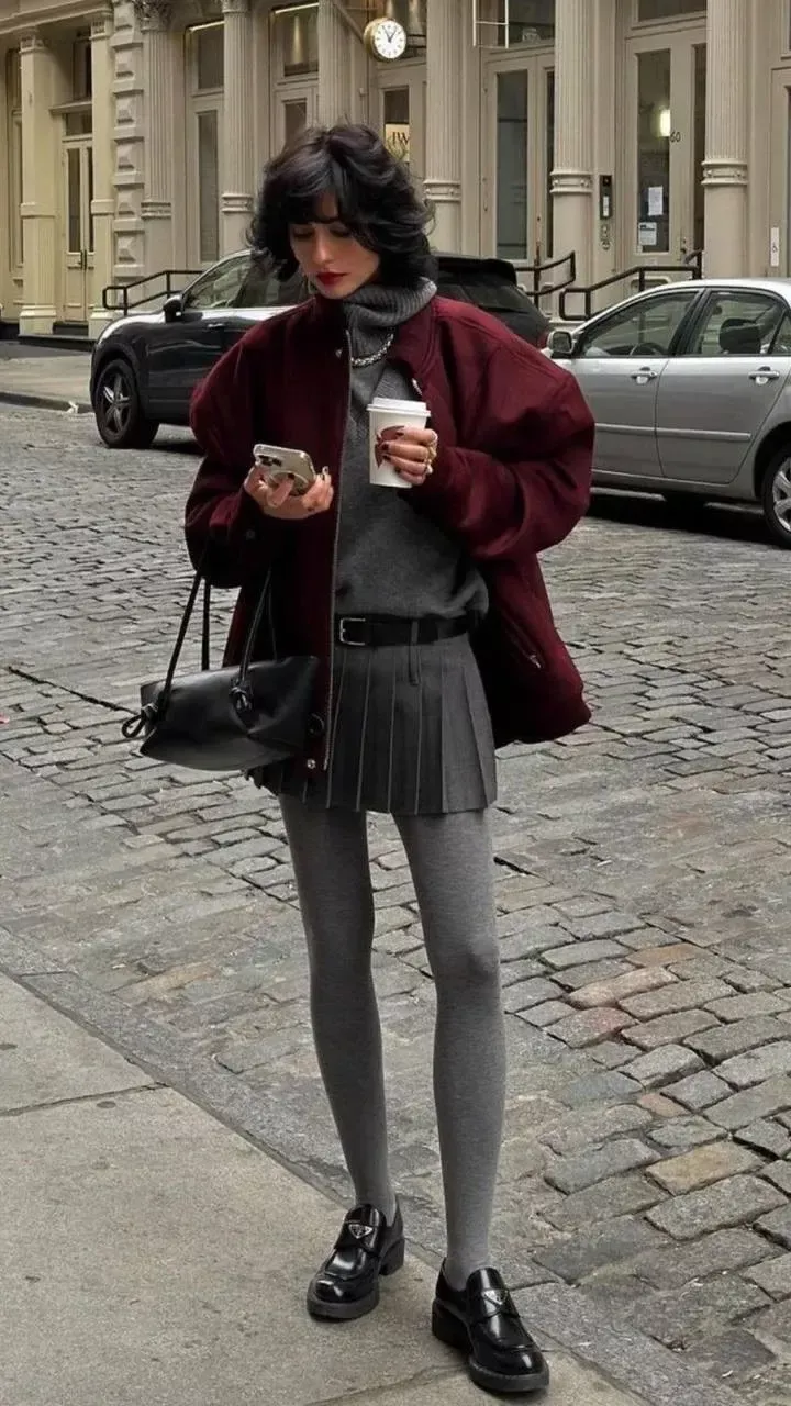 Woman in a red jacket and pleated skirt on a cobblestone street