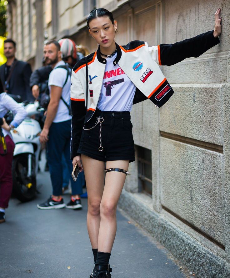 Woman in a racing jacket and black shorts with a spiked garter on a street