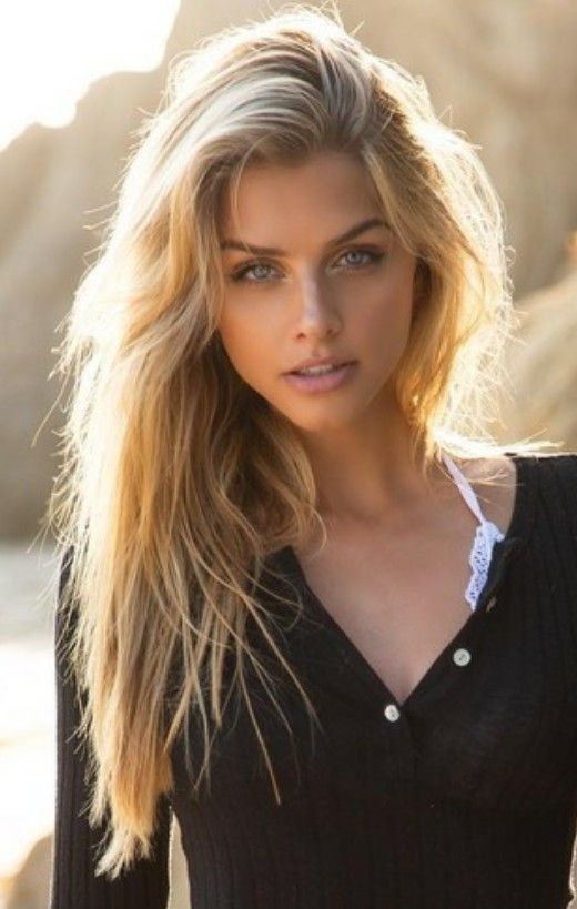 Blonde woman with blue eyes wearing a black shirt and white bra outdoors
