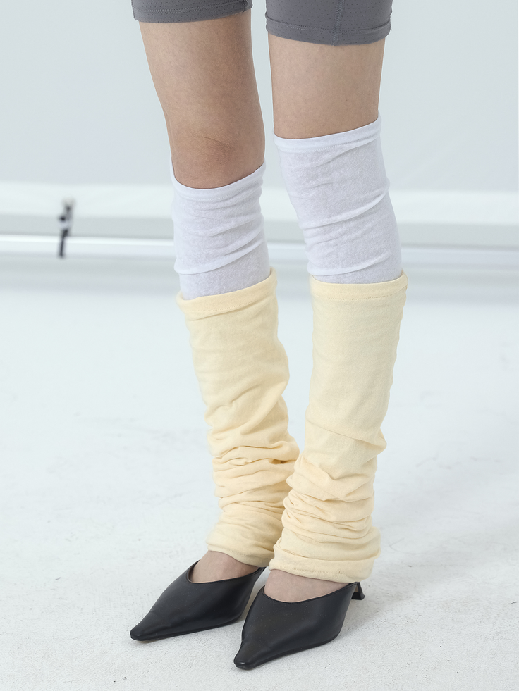 Person wearing gray shorts, white socks, yellow leg warmers, and black heels