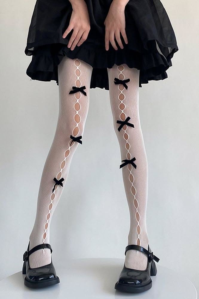 Person wearing white tights with black bows and black mary jane shoes