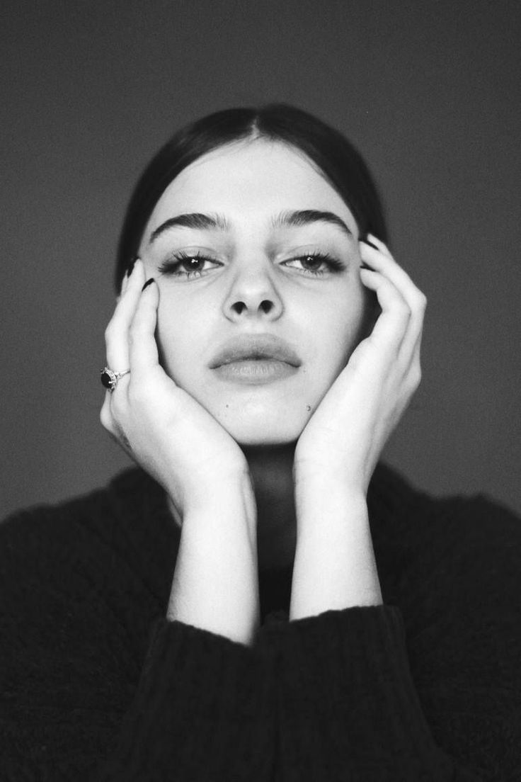 Woman with dark hair wearing a sweater and a ring, shot in black and white