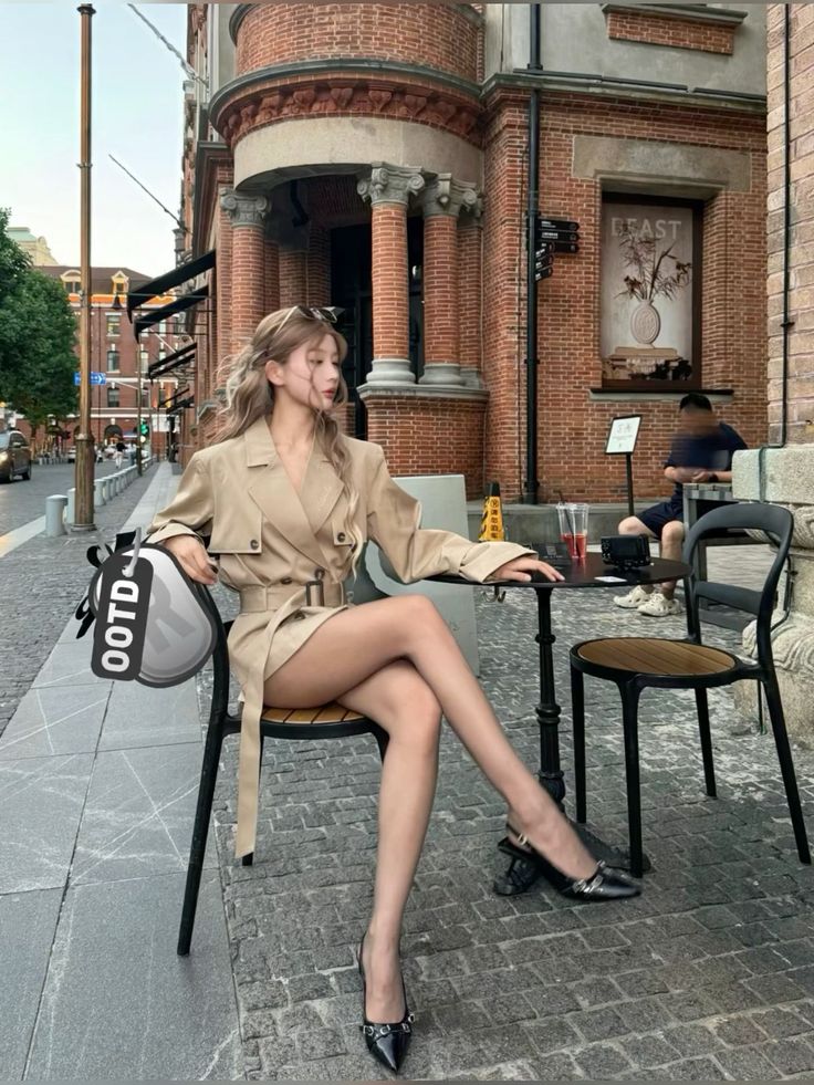 Woman in a trench coat dress sitting at an outdoor cafe table