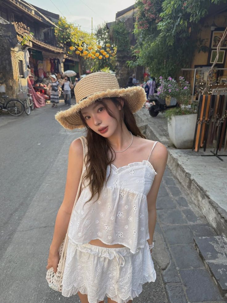 Woman in a straw hat and white outfit on a street