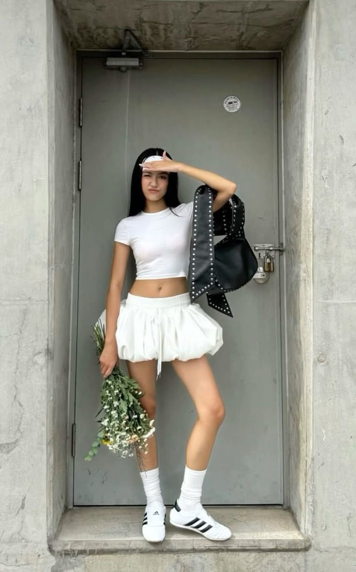 Woman in a white crop top and bubble skirt holding flowers