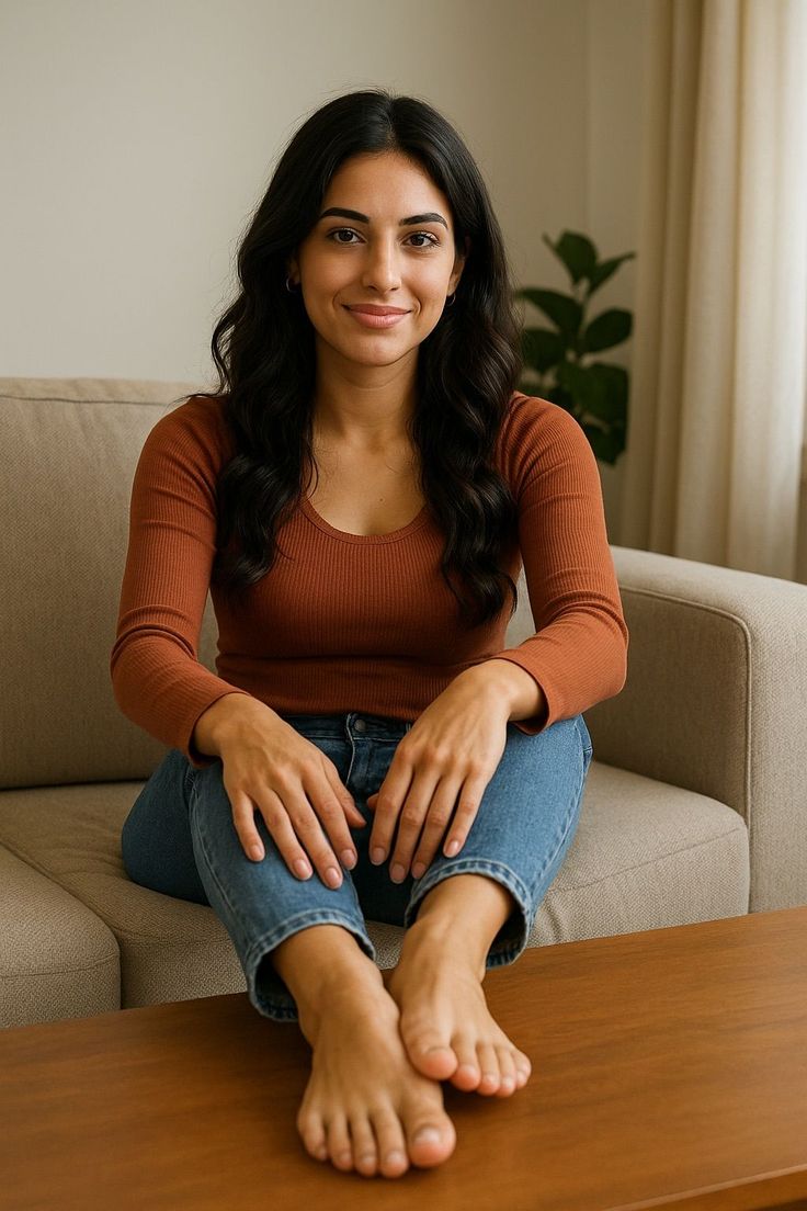 Woman with long dark hair sitting on a couch with bare feet on a coffee table