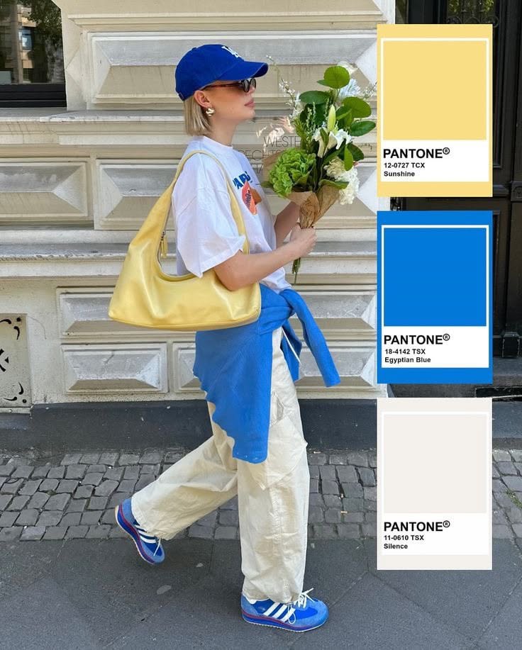 Person in a blue cap and sunglasses holding flowers on a street