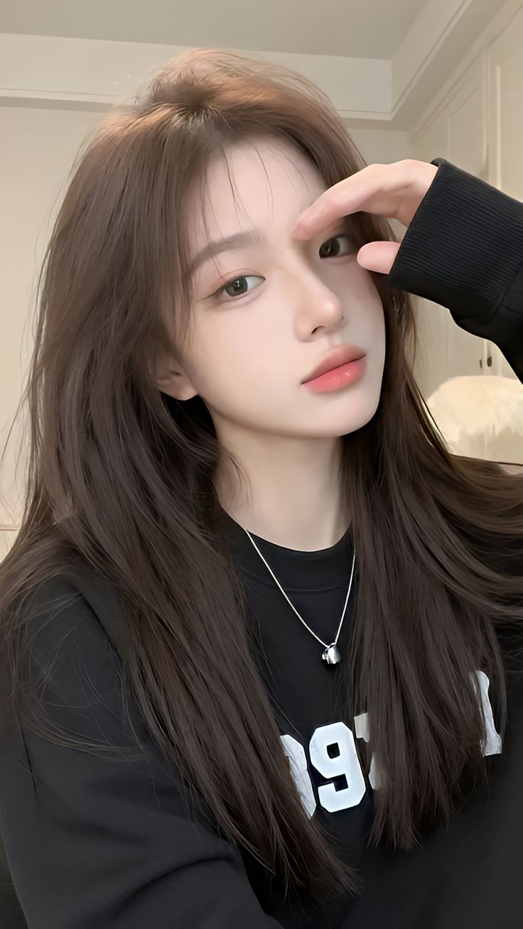 Woman with long brown hair wearing a black top and silver necklace