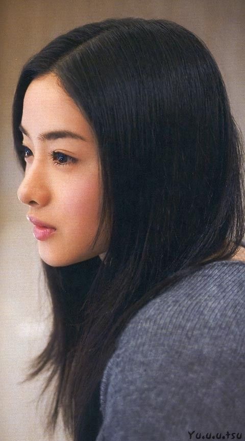 Woman with long black hair in a grey sweater, captured in a soft-lit side profile