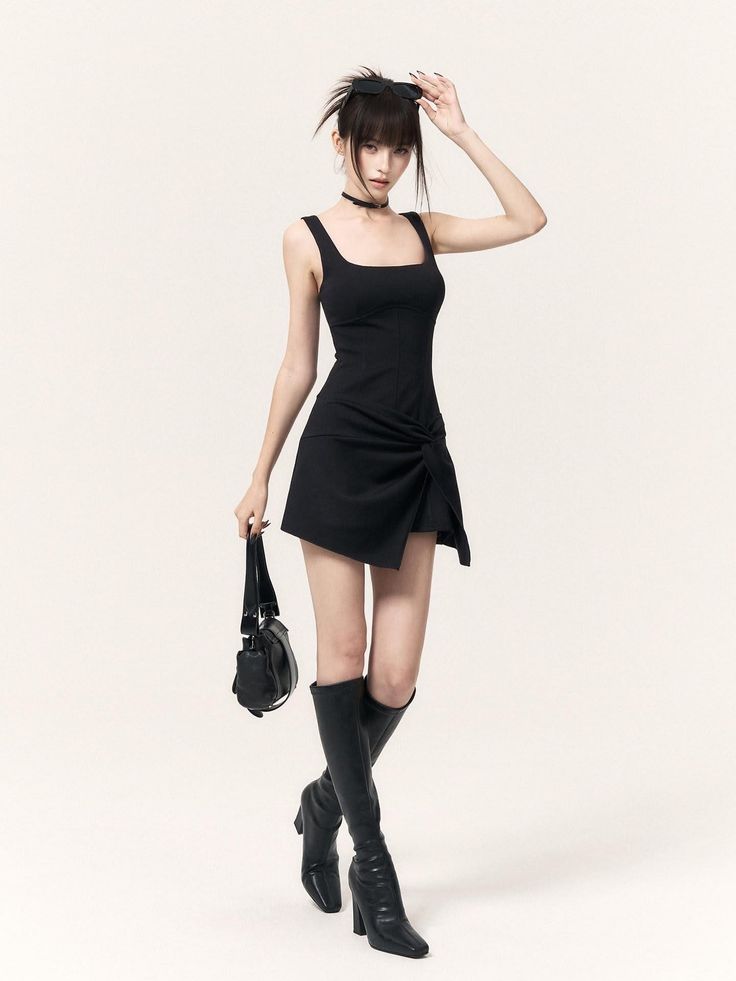Woman in a black dress and knee-high boots holding sunglasses on a white background
