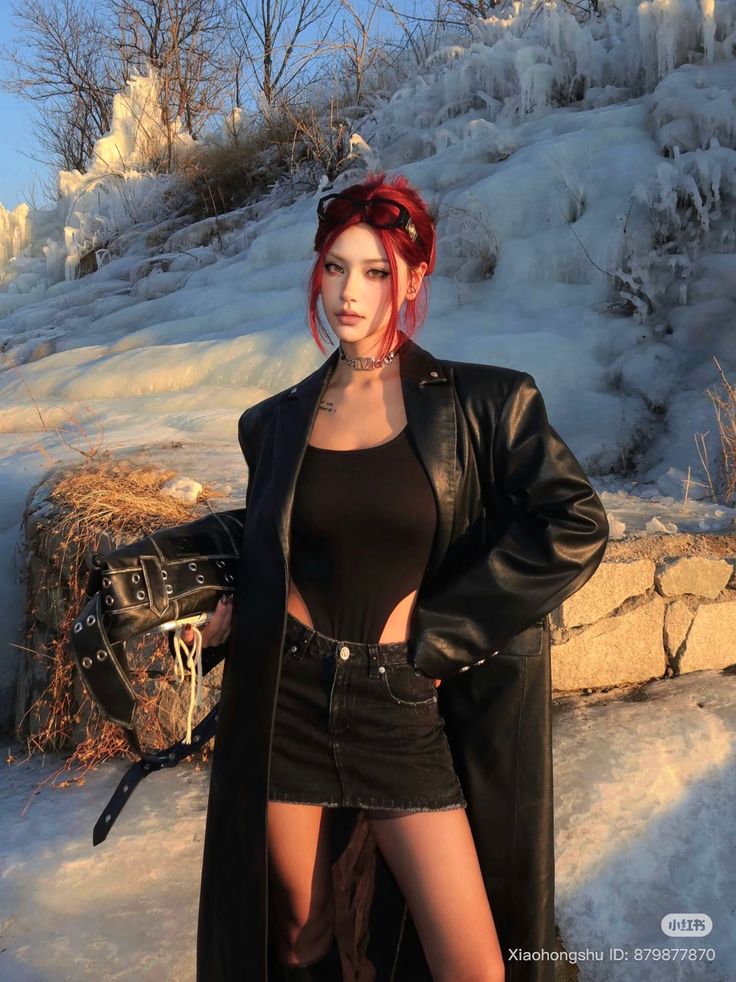Woman with red hair in a black leather coat and denim skirt outdoors in winter