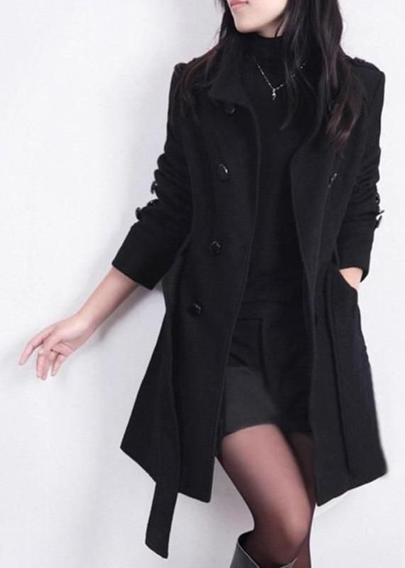 Woman in a black coat, turtleneck, shorts, and tights posing against a white background