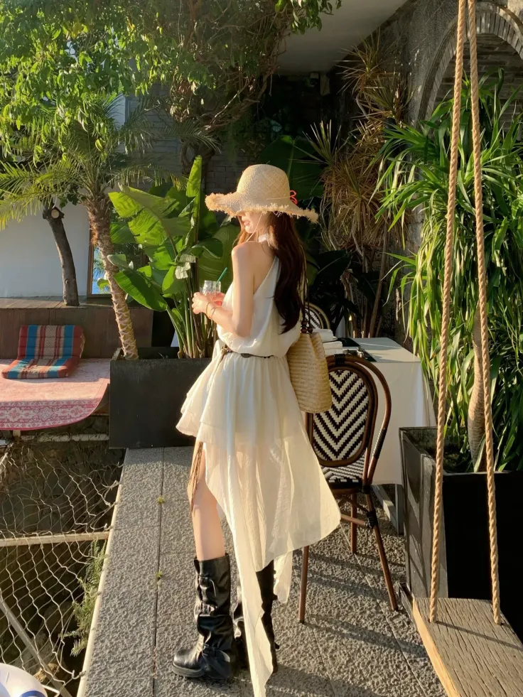 Woman in a white dress and straw hat outdoors during golden hour
