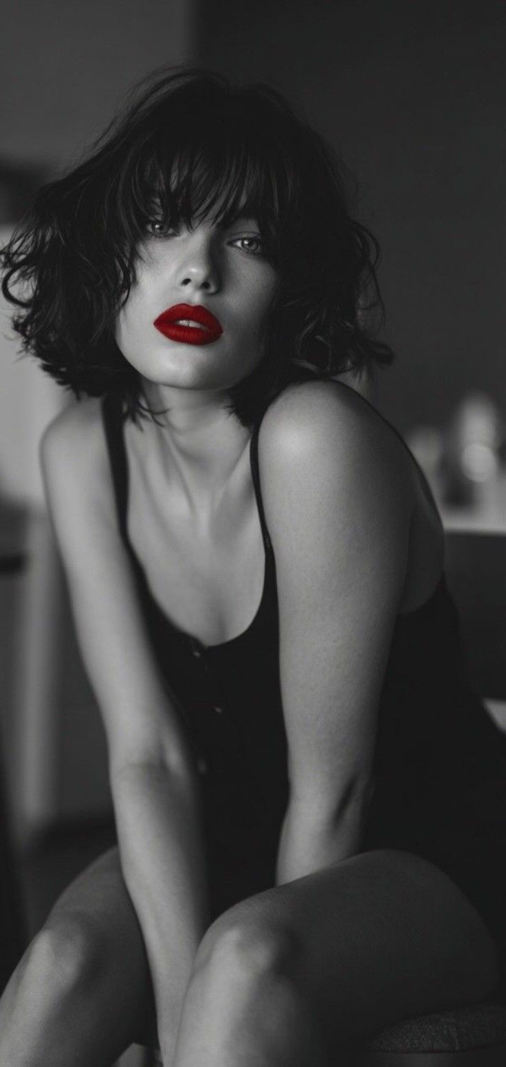 Woman with short dark hair and red lipstick in a black and white photograph