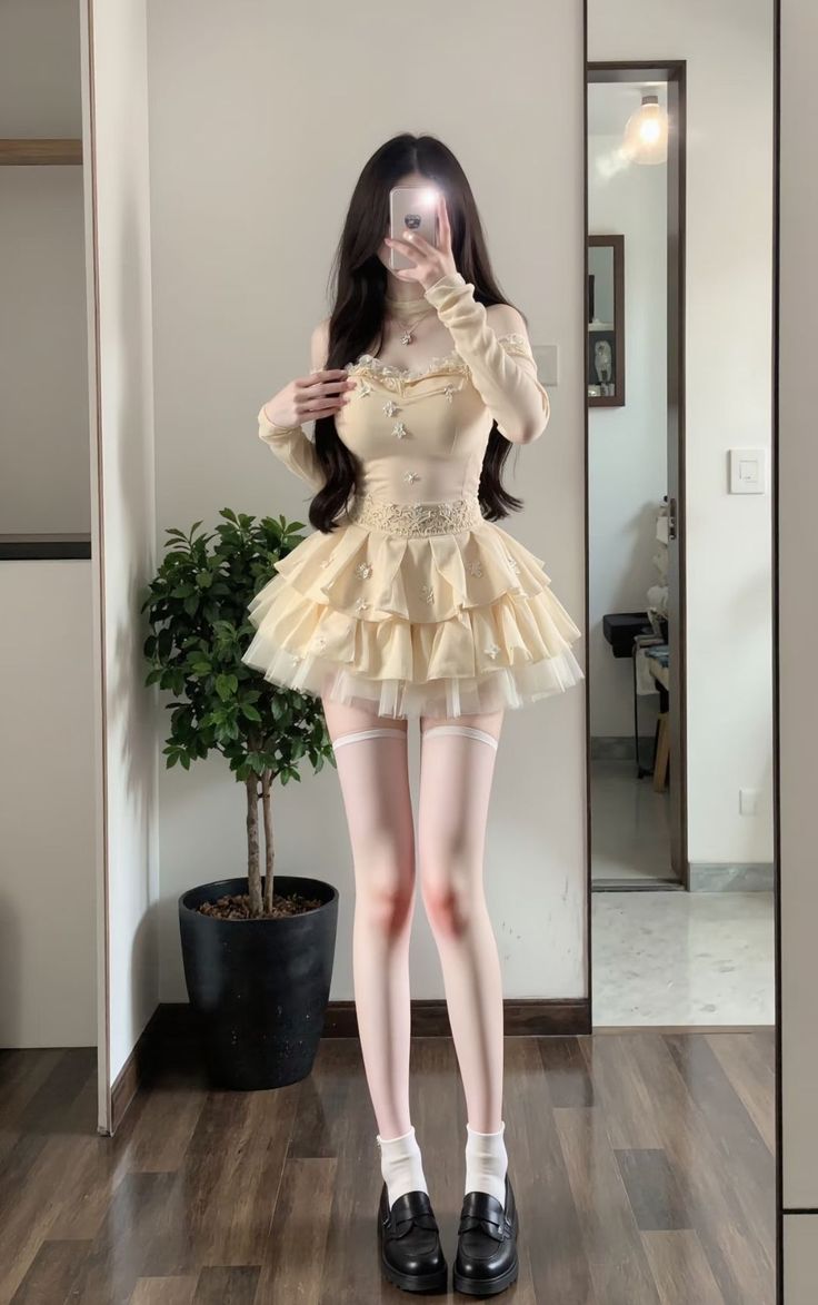 Woman in a ruffle dress and thigh high socks taking a mirror selfie
