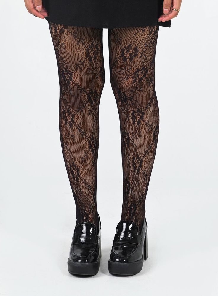 Person wearing black lace tights and platform shoes with a black skirt